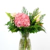Pink hydrangea bouquet with cream roses in a clear glass vase