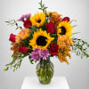 Bouquet of sunflowers, red roses, and purple mums in a glass vase