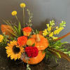 Orange pumpkin-shaped vase with sunflowers, roses, and yellow blooms