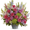 Abundant pink and purple mixed flower arrangement with green hydrangeas in a gray ceramic pot