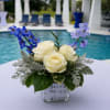 A custom-designed floral arrangement featuring elegant white roses, fresh greenery, and soft