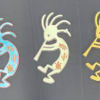Three colorful Kokopelli-style wall decorations on a dark background