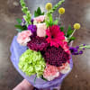 Bouquet of pink, purple, and green flowers wrapped in lavender paper
