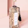 Clear glass bottle with gold cap and black tassel label