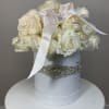 White roses arranged in a round hat box with a satin ribbon
