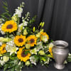 Sunflower and white floral arrangement beside a silver urn