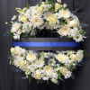 White floral funeral wreath with roses and daisies on a black stand