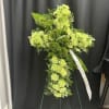 Green floral standing cross with a white ribbon on an easel