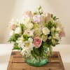 Pink and white flower arrangement in a green glass vase