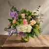 Mixed bouquet of pastel flowers in a clear glass vase