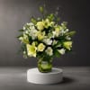 White and pale yellow floral arrangement in a glass vase