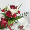 Red roses and white flowers in a mug with a ribbon bow