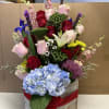Mixed bouquet in a wooden box with roses, hydrangea, and lilies