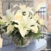 White lilies and cream roses arranged in a glass vase