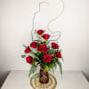 Red roses arranged in a tall vase with curly branches