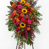 Tall standing floral spray with roses, sunflowers, lilies, and mixed blooms