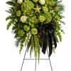 Green floral standing spray with white roses and a black ribbon on an easel