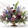 Mixed floral arrangement in a gold pedestal vase with purple, white, and green blooms