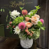 Mixed bouquet of peach roses, pink dahlias, and white chrysanthemums in a white vase