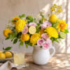 Yellow and pink flowers arranged in a white pitcher with citrus slices