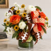 Bouquet of orange and white flowers in a glass vase with football ribbons