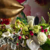 Mixed floral arrangement in a glass vase with white calla lilies, roses, and orchids