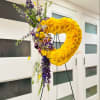 Large yellow floral heart on a black stand with purple flowers cascading down one side