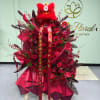 Large red floral arrangement with roses and ribbons, topped by a red lion head decoration