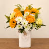 Yellow and white flower arrangement in a white ceramic vase