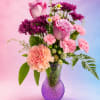 Pink and purple mixed bouquet in a purple glass vase