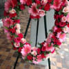 Heart-shaped floral wreath with pink and red roses and daisies on an easel