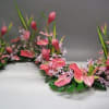 Pink floral garland with tall green leaves on a table