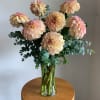 Peach-pink dahlias in a clear glass vase with eucalyptus