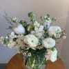 White floral bouquet in a clear glass vase on a wooden table
