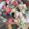 Bouquet of pink tulips and pale flowers wrapped in brown paper