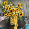 Sunflower arrangement in a clear vase with lemons and trailing yellow flowers