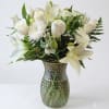 White lilies and roses arranged in a textured glass vase