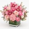 Pink floral arrangement in a clear square vase