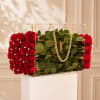 Red roses arranged in a clear acrylic box with a gold chain handle