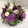 Mixed purple and white flowers arranged in a glass vase