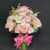 Pink roses and carnations in a glass vase with a bright pink bow