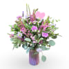 Pink and lavender mixed bouquet in a purple glass vase with a heart pick