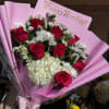 Bouquet of red roses and white flowers in pink wrapping with a Happy Birthday card
