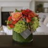Orange and peach roses with green hydrangeas in a glass vase