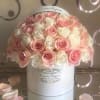 Pink and white roses arranged in a round white hat box