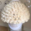 Large round hatbox filled with tightly packed ivory roses on a reflective stand