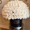 Dome of ivory roses arranged tightly in a black round hat box with gold lettering