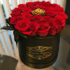 Red roses arranged in a black round box with a gold rose accent