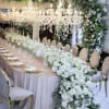 White floral wedding table with chandeliers and a long centerpiece