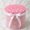 Round pink box filled with pink roses and tied with a white ribbon